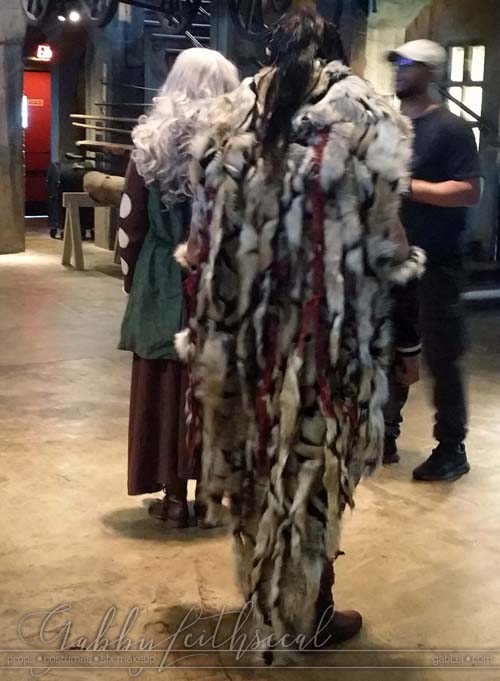 BTS back view of man wearing The Beast costume long red, black and brown fur cloak.