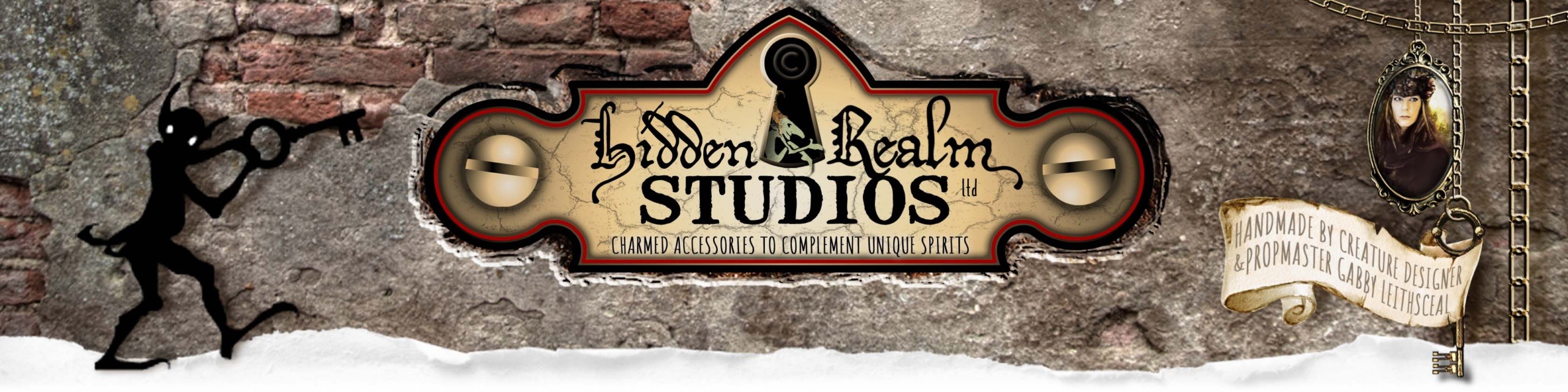 Hidden Realm Studios logo is displayed on an old plaster brick wall. Chains hang from the side, holding a skeleton key, a locket featuring the artist, and a scroll displaying the artist's name. A playful goblin shadow holds a shadow copy of the skeleton key.