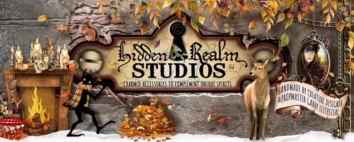 Hidden Realm Studios logo surrounded by autumn's essence: falling leaves, a cozy fireplace, woodland creatures, candles, and a playful goblin shadow in a scarf raking leaves.